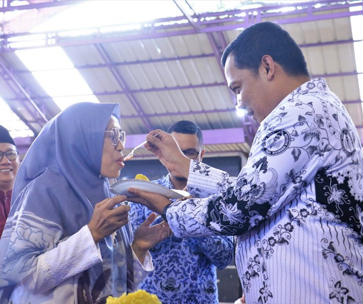 Pj Wali Kota Muflihun memberikan suapan nasi tumpeng pertama kepada mantan gurunya di SMAN 1 Pekanbaru di Hari Guru, Jumat (24/11/2022). Foto: Istimewa.