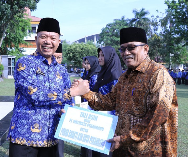 Pj Sekdako Pekanbaru Indra Pomi Nasution saat menyerahkan santunan kepada 50 pensiunan PNS saat upacara Hari KORPRI di lapangan MPP, Selasa (29/11/2022). Foto: Istimewa.