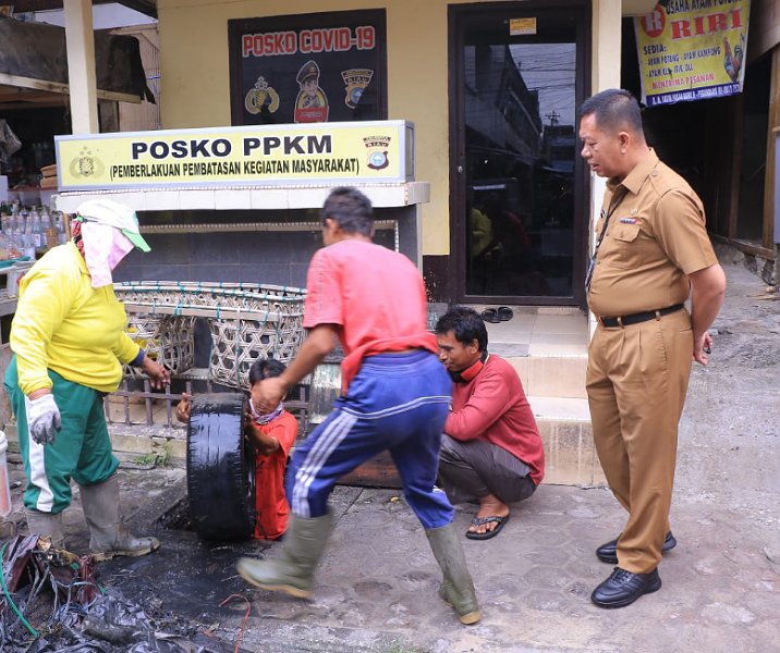 Pj Sekdako Pekanbaru Indra Pomi Nasution melihat ban mobil dikeluarkan pasukan kuning Dinas PUPR dari dalam drainase Pasar Bawah, Senin (19/12/2022). Foto: Istimewa.