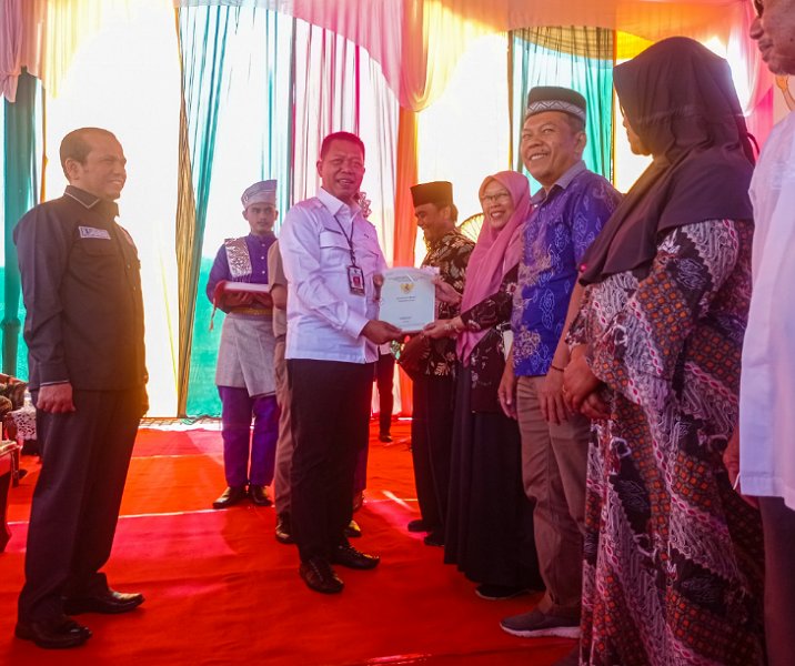 Pj Sekdako Pekanbaru Indra Pomi Nasution menyerahkan sertifikat tanah kepada warga yang ikut program PTSL di halaman Masjid Az Zahidin, Jalan Tenayan, Tenayan Raya, Jumat (3/2/2023). Foto: Surya/Riau1.