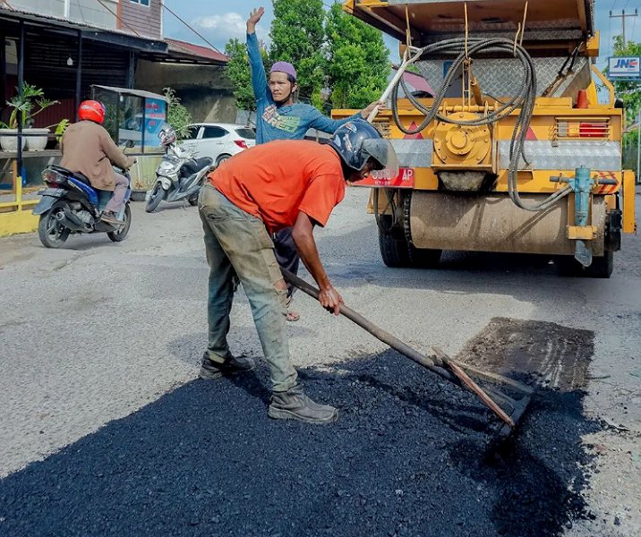 Seorang pekerja Dinas PUPR Pekanbaru tengah menambal lubang di salah satu jalan di Pekanbaru. Foto: Istimewa.