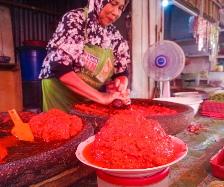 Pedagang Pasar CIk Puan sedang menggiling cabai merah. Foto: Surya/Riau1.