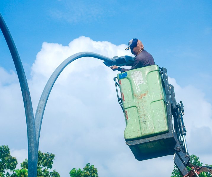 Seorang pekerja mengganti bola lampu PJU di Jalan Jenderal Sudirman Pekanbaru. Foto: Istimewa.