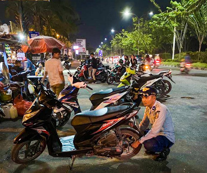Petugas Dishub Pekanbaru mengempeskan ban motor yang parkir sembarangan di sekitar Mal SKA. Foto: Istimewa.