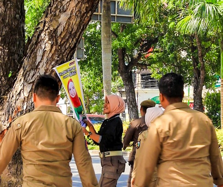 Petugas Satpol PP Pekanbaru menertibkan poster caleg di pepohonan Jalan Jenderal Sudirman pada 24 Agustus 2023. Foto: Istimewa.