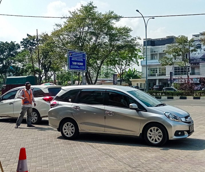 Seorang jukir saat memandu mobil keluar dari area parkir. Foto: Surya/Riau1.
