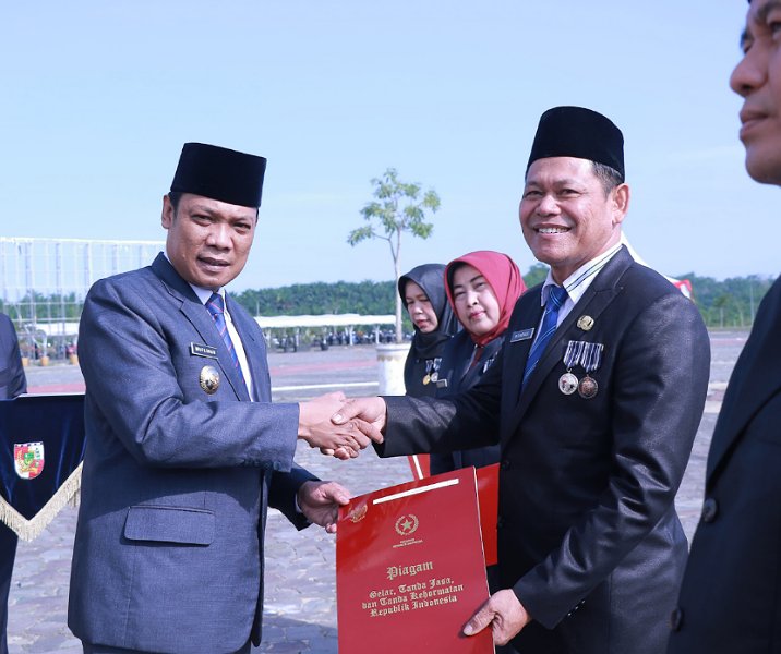 Pj Wali Kota Pekanbaru Muflihun menyerahkan piagam tanda jasa Satyalancana Karya Satya kepada Kepala Distankan M Firdaus saat upacara Hari Pahlawan di lapangan Gedung Utama Kompleks Perkantoran Tenayan Raya, Jumat (10/11/2023). Foto: Istimewa.