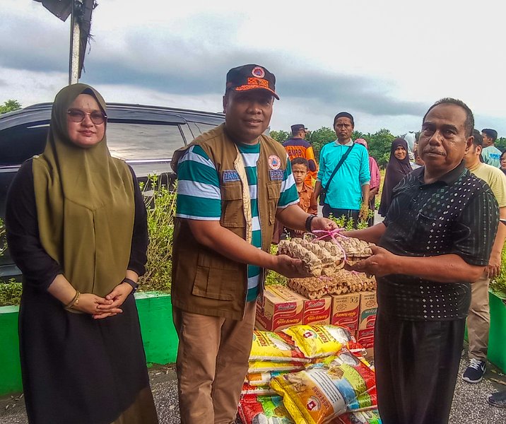 Kalaksa BPBD Pekanbaru Zarman Candra didampingi Camat Rumbai Vemy saat menyalurkan bantuan makanan kepada ketua RW 16, Jalan Nelayan, Kelurahan Sri Meranti, Sabtu (13/1/2024). Foto: Surya/Riau1.