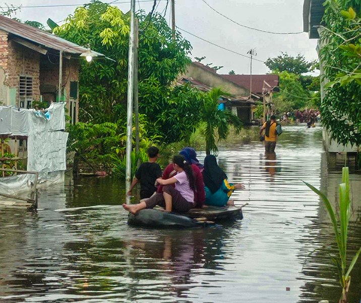 Warga Perumahan Witayu menggunakan ban mobil bekas menuju rumahnya saat banjir pekan lalu. Foto: Surya/Riau1.