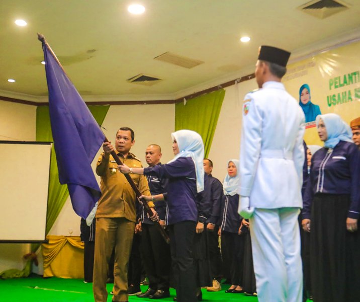Pj Wali Kota Pekanbaru Muflihun mengibarkan bendera Forum UMKM bersama ketua forum Raja Rilla Muflihun saat prosesi pelantikan di Hotel Mutiara Merdeka, Selasa (30/1/2024). Foto: Istimewa.
