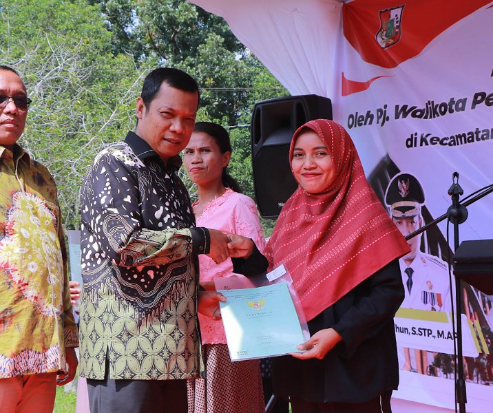 Pj Wali Kota Pekanbaru Muflihun menyerahkan sertifikat tanah kepada warga di halaman Kantor Kecamatan Rumbai Barat pada 8 Februari 2024. Foto: Istimewa.
