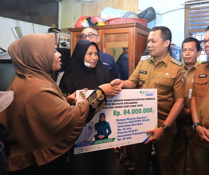 Pj Wali Kota Pekanbaru Muflihun menyerahkan jaminan kematian kepada ahli waris petugas KPPS secara simbolis di Jalan Imam Bonjol, Selasa (27/2/2024). Foto: Istimewa.