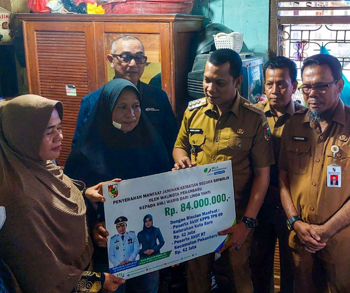 Pj Wali Kota Pekanbaru Muflihun didampingi Kepala BPJS Ketenagakerjaan Iman Santoso menyerahkan santunan atau manfaat jaminan kematian kepada salah seorang ahli waris petugas Pemilu, Selasa (27/2/2024). Foto: Istimewa.