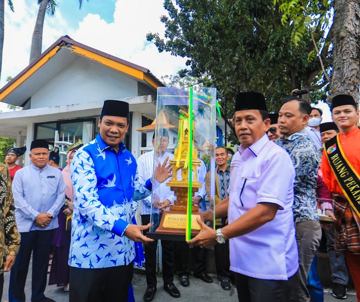 Pj Wali Kota Pekanbaru Muflihun menerima piala bergilir MTQ Riau dari Ketua LPTQ Idrus di halaman rumah dinas wali kota, Minggu (28/4/2024). Foto: Istimewa.