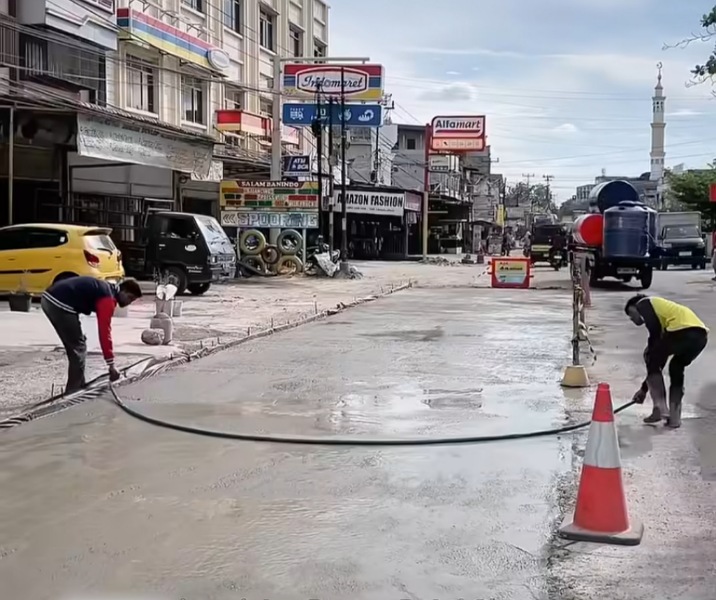 Pekerja Dinas PUPR Pekanbaru meratakan cor semen di Jalan Darma Bakti. Foto: Istimewa.
