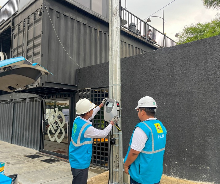 Dua petugas PLN sedang memasang perangkat wall charger untuk kendaraan listri di halaman parkir Kedai Kopi Monocsky, Jalan Pramuka, Rumbai Timur, Pekanbaru. Foto: Istimewa.