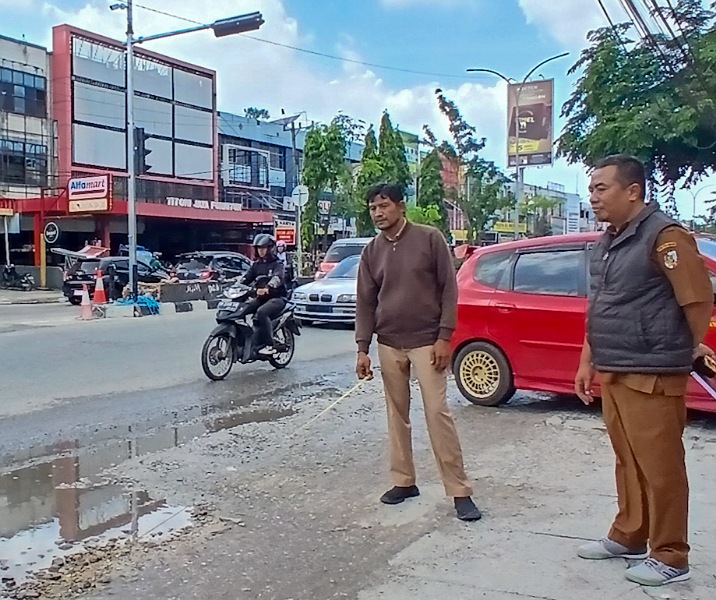 Pegawai Dinas PUPR Pekanbaru mengukur panjang jalan yang rusak di persimpangan Jalan Tuanku Tambusai-Paus, Selasa (13/1/2026). Foto: Surya/Riau1.