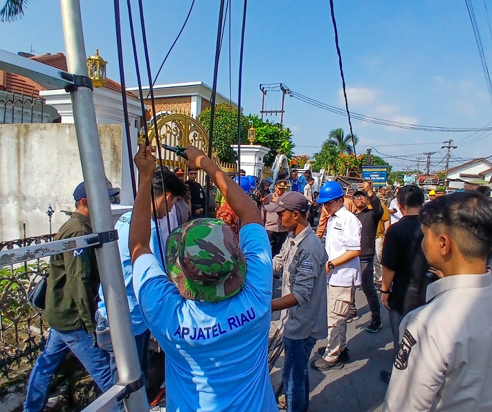 Pihak APJATEL Riau ikut memotong kabel fiber optik yang sudah tak aktif di Jalan Ronggowarsito, Jumat (5/6/2026). Foto: Surya/Riau1.