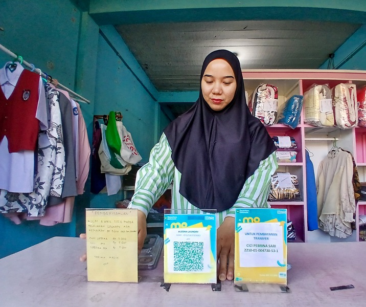 Cici, pemilik usaha Alesha Laundry, menunjukkan QRIS BRI yang telah dipakai sejak dua tahun lalu. Foto: Surya/Riau1.