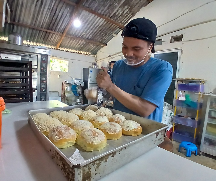 Oktanus sedang memarut keju di atas kue yang sudah dipanggang. Foto: Surya/Riau1.