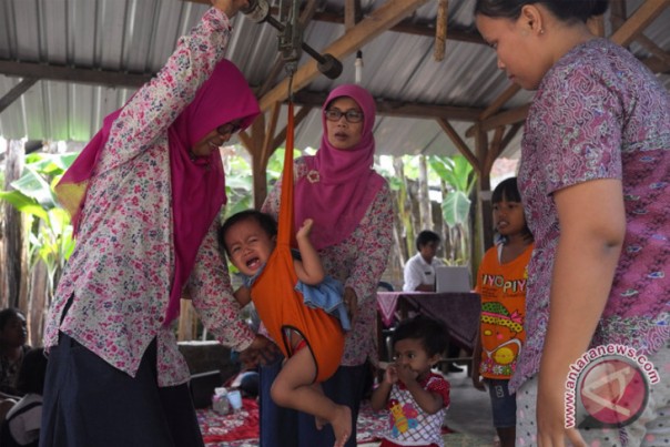 Ilustrasi Kader Pos Yandu sedang menimbang balita untuk mengatasi gizi agar anak tidak kerdil.