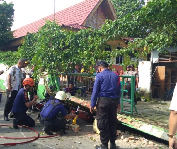 Petugas saat mengevakuasi pasca runtuhnya tembok sekolah di Pekanbaru