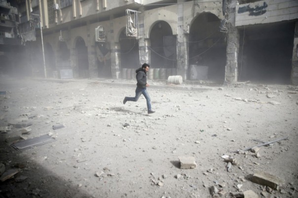 Seorang laki-laki berlari menghindari serangan udara di Suriah. 
