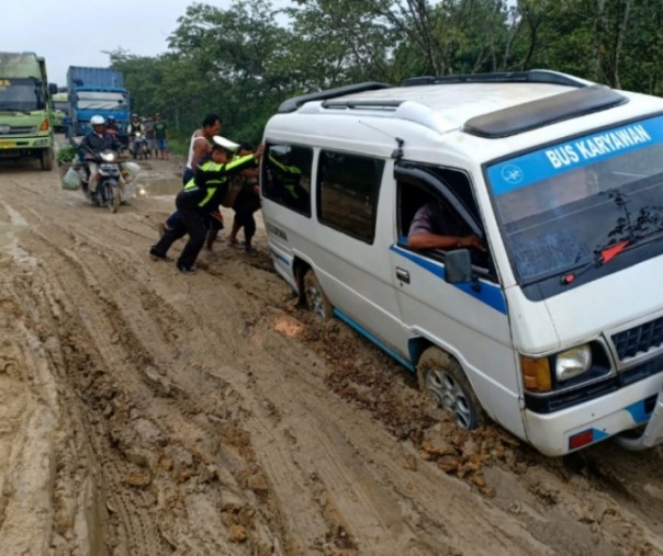 Tampak petugas kepolisian bersama masyarakat berupaya mengevakuasi kendaraan yang terperosok di jalan rusak dekat jembatan Maredan, Perawang pada Sabtu siang