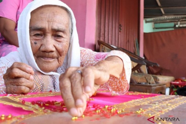 Nenek Nuraya sedang memilih manik-manik untuk baju pengantin Pariaman tanpa memakai kaca mata. 