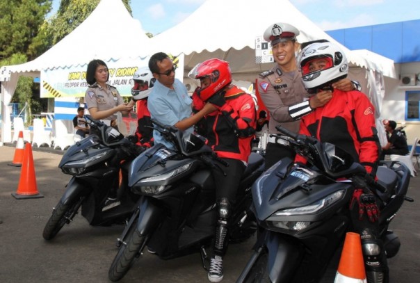 GM Corporate Communication PT Astra Honda Motor Ahmad Muhibbuddin (Tengah) didampingi oleh Briptu Vanesha (Kiri) dari NTMC Polri dan Bripka Malvinas (Kanan) dari Korlantas melakukan penyematan helm ke para peserta sebagai tanda dibukanya sesi praktek pada acara Safety Riding Camp 2019