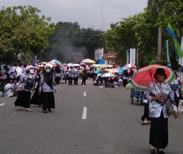 Ratusan guru sertifikasi bertahan hingga siang. Mereka menggunakan payung untuk melindung dari cuaca panas, Kamis (21/3/2019). Foto: Surya/Riau1.