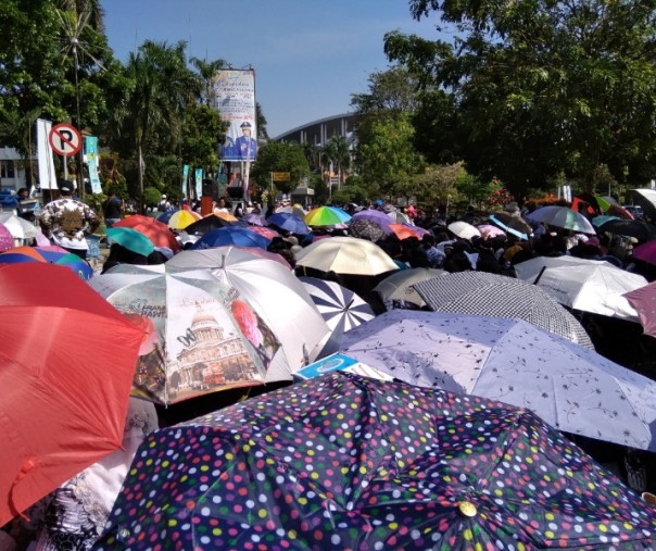 Ratusan payung dikembangkan para guru sertifikasi untuk menutupi badan dari cuaca panas saat berdemo di depan kantor wali kota Pekanbaru, Jumat (22/3/2019). Foto: Surya/Riau1.