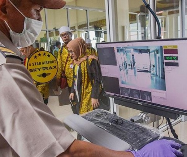 Seorang petugas Kantor Kesehatan Pelabuhan mengoperasikan alat pemindai panas tubuh di terminal kedatangan internasional Bandara Sultan Syarif Kasim II di Kota Pekanbaru, Riau, Selasa (14/5/2019). Foto: Antara.