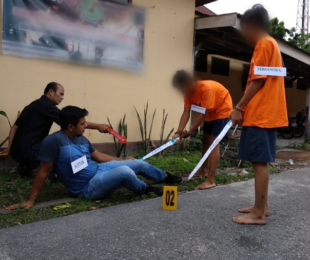 Dua tersangka tengah memeragakan adegan yang terjadi saat penyerangan terhadap Angga. Reka ulang ini digelar di halaman Polsek Tampan, Rabu siang (Foto: Riau1)