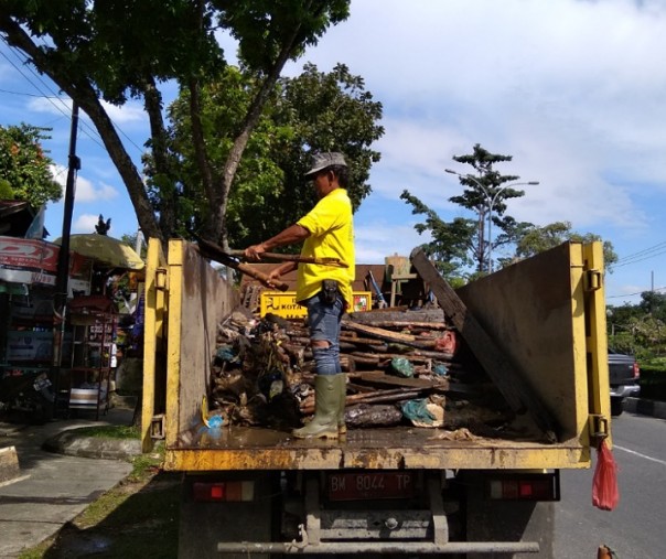 Seorang pekerja sedang menyusun sampah di atas truk pengangkut saat pembersihan parit Jalan Arifin Ahmad Pekanbaru. Foto: Surya/Riau1.