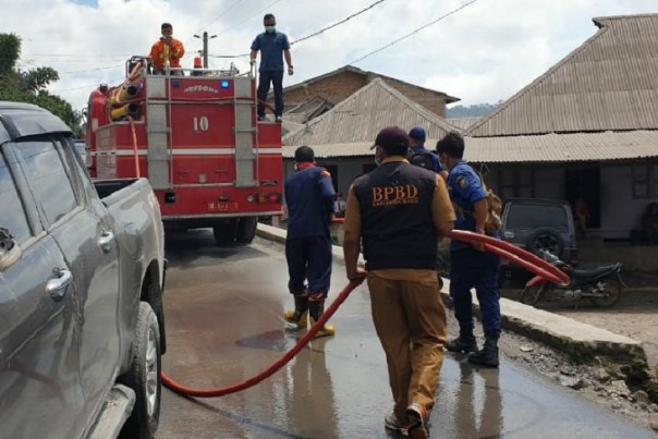Petugas menggunakan mobil pemadam kebakaran untuk membersihkan debu erupsi Gunung Sinabung, Sumatera Utara, Senin sore. 