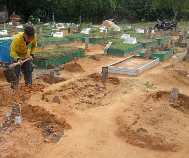 Seorang petugas jaga kubur memadatkan tanah kuburan yang ambruk di TPU Payung Sekaki, Kamis (13/6/2019).