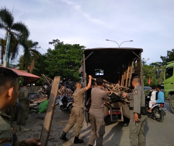 Personel Satpol PP Pekanbaru saat membongkar dan menyita potongan kayu yang dijadikan lapak dagangan di seberang Pasar Simpang Baru Panam, Jumat (26/6/2019). Foto: Surya/Riau1.
