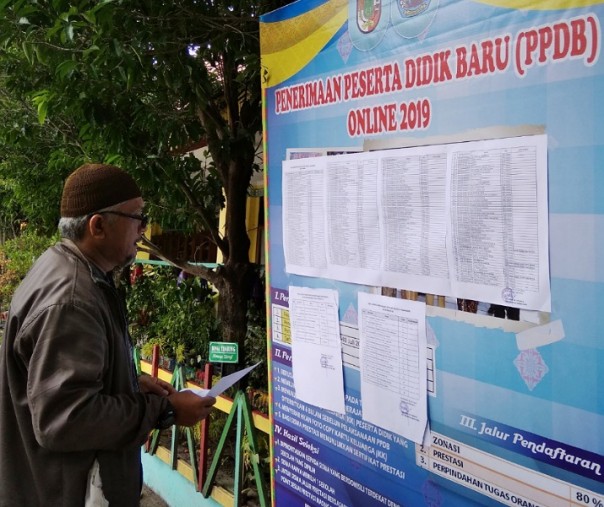 Salah seorang orangtua saat mencari nama anaknya yang diterima melalui jalur prestasi di SMPN 5 Pekanbaru. Foto: Surya/Riau1.