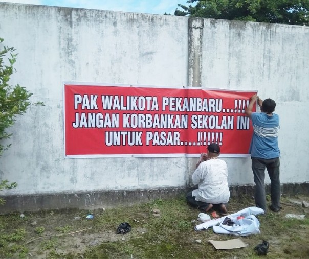 Wali murid saat memasang spanduk protes untuk Wali Kota Pekanbaru Firdaus di kompleks SDN 01, SDN 10, dan SDN 156, Jalan Ahmad Yani, Rabu (10/7/2019).