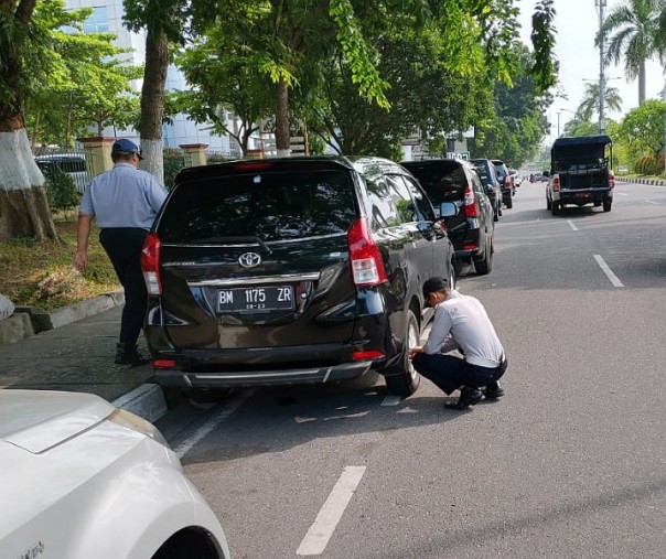 Petugas Dishub Pekanbaru saat menggembosi sejumlah mobil yang parkir di jalur sepeda, tepatnya di samping Rumah Sakit Arifin Achmad, Rabu (17/7/2019). Foto: Istimewa.