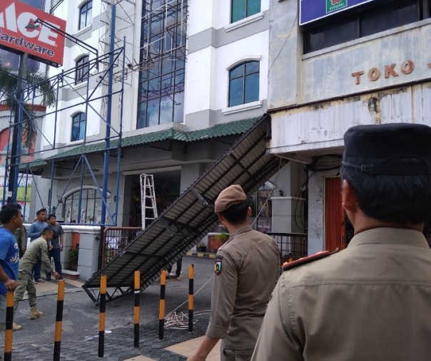 Petugas Satpol PP Pekanbaru saat memotong atap kanopi ruko di Jalan Jenderal Sudirman, beberapa waktu lalu. Foto: Surya/Riau1.