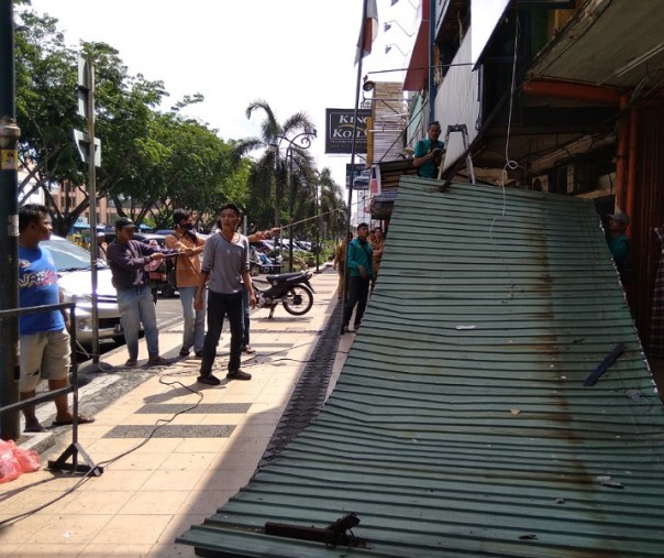 Petugas Dinas PUPR Pekanbaru saat mencabut kanopi ruko di Jalan Jenderal Sudirman, beberapa waktu lalu. Foto: Surya/Riau1.