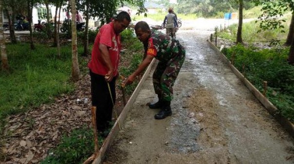 Anggota Koramil 07 Kampar saat membantu warga Desa Padang Mutung melakukan semenisasi jalan