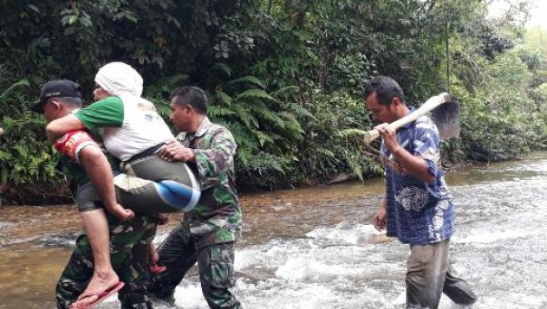 Anggota Satgas TMMD Kodim 0313/KPR saat membantu seorang lansia menyeberangi sungai di Dusun V Sei Asam 