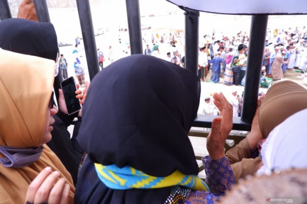 Istri Mbah Moen (berkerudung hitam) menyaksikan kepergian sang suami dari balik pagar Pemakaman Ma'la Mekkah, Selasa. 