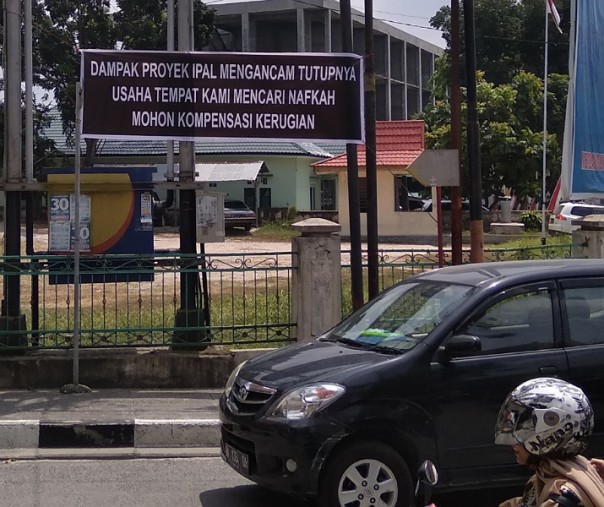 Spanduk protes dan permintaan kompensasi akibat proyek Kementerian PUPR di Kecamatan Sukajadi, Pekanbaru, Senin (5/8/2019). Foto: Surya/Riau1.