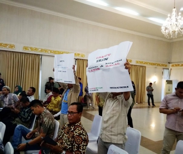 Dua mahasiswa Unri membentangkan tulisan saat rapat karhutla (Foto: Zar/Riau1.com)
