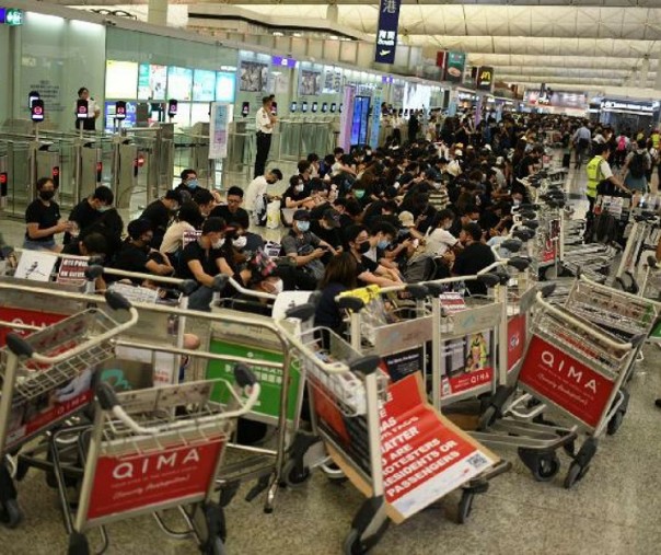 Pengunjuk rasa membangun blokade dari troli bagasi di sekitar pintu masuk ke area keamanan di bandara Hong Kong. Foto: CNN.