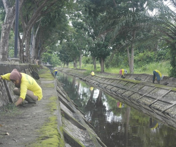 Petugas kebersihan membersihkan pinggiran parit dari sampah di Jalan Datuk Setia Maharaja, Pekanbaru. Foto: Surya/Riau1.